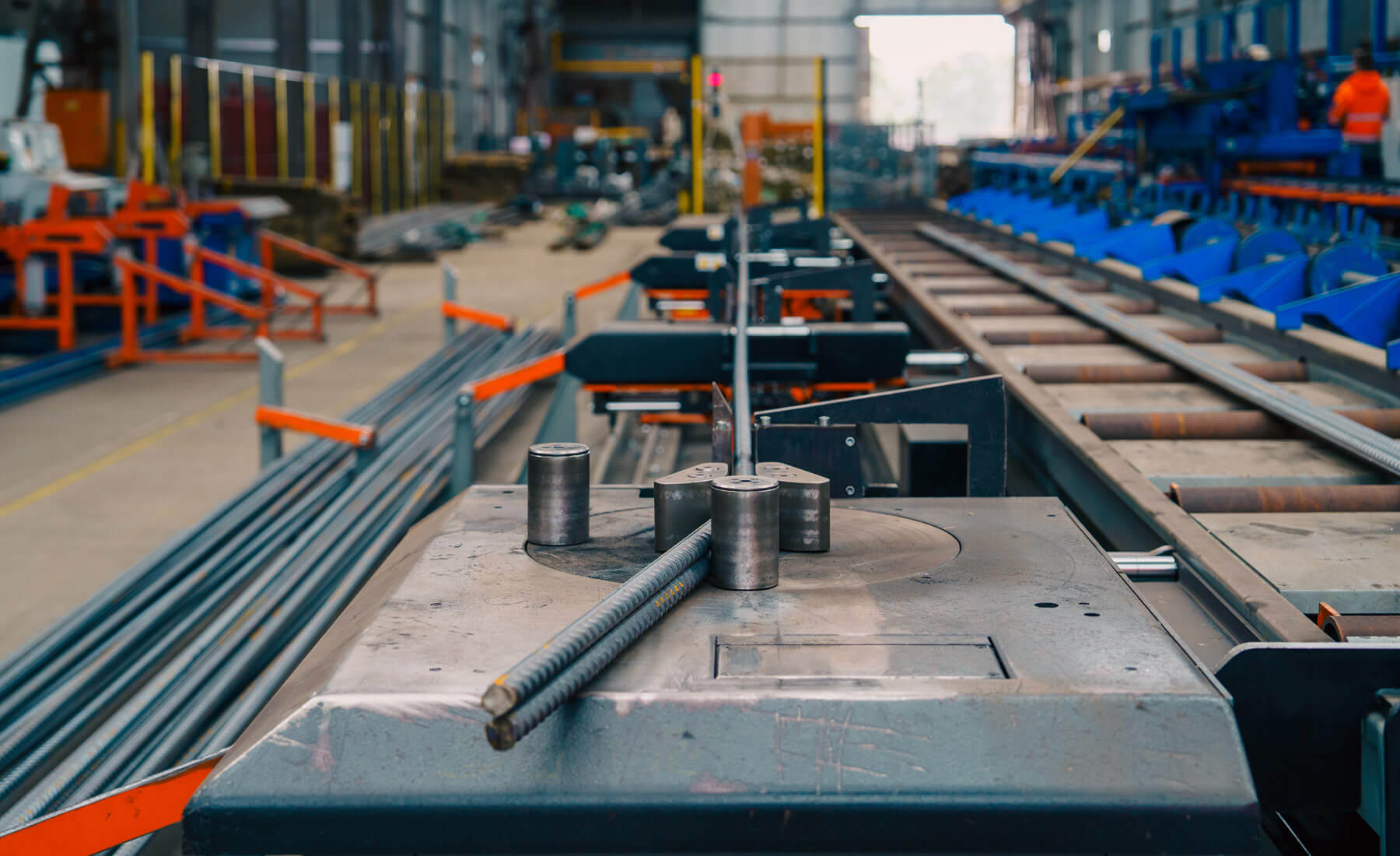 Close up of a long machine that bends steel reinforcing bars.