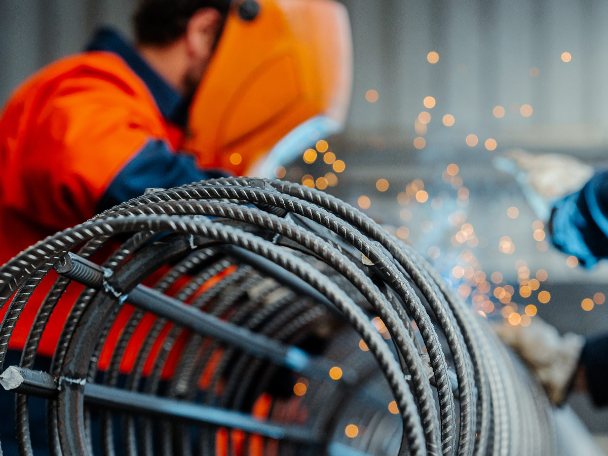 Close up photo of man wearing welding mask and welding steel reinforcing